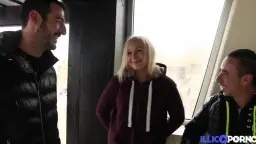 Blonde Frau auf Knien, zwei Schwänze im Mund